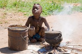 Namibija – deček plemena Himba kuha kosilo