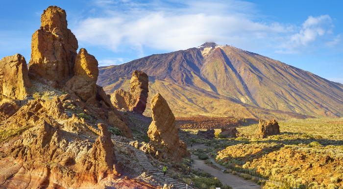 Pogled na mogočni vulkan Teide obdan z vulkanskimi skalami in sončno pokrajino na otoku Tenerife