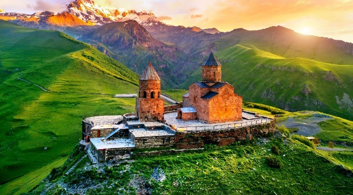 Obdana z zelenimi gorami stoji na griču starodavna gruzijska cerkev Gergeti