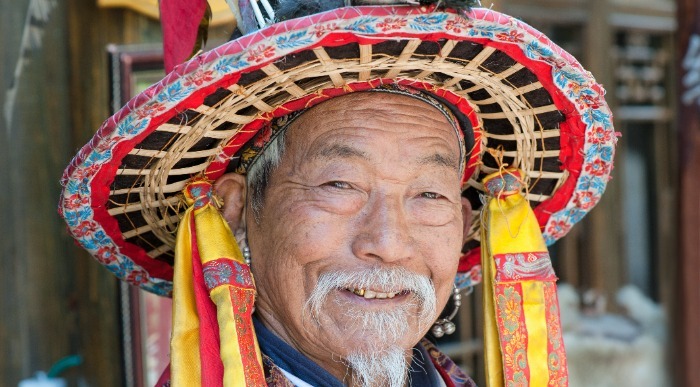 Nasmejani kitajski gospod z tradicionalnim pisanim klobukom.