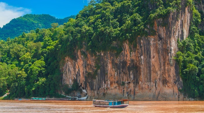 Vožnja z tradicionalno leseno ladjo po reki oranžne barve.