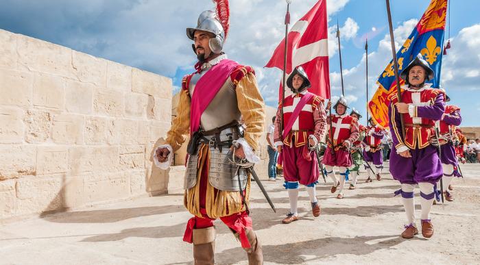 Malteški vitezi v svoji tipični uniformi nosijo zastavo. 