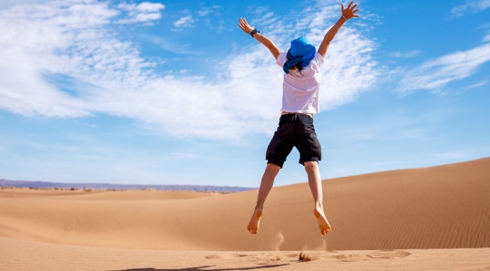 Visok skok v zrak fanta po puščavskem pesku. 