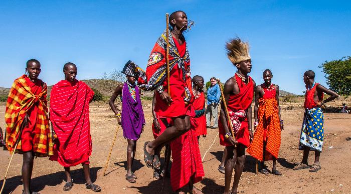 Masaji oblečeni v rdeče in pisane tkanine izvajajo tradicionalni afriški ples