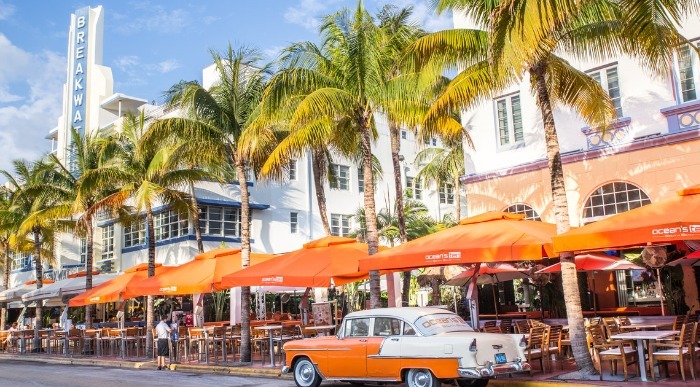 Ulica z art deco stavbami in palmami ter starodobnim avtomobilom v Miami Beachu na Floridi