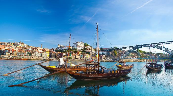 Ladjice na reki Douro plujejo ob jasnem sončnem vremenu.      