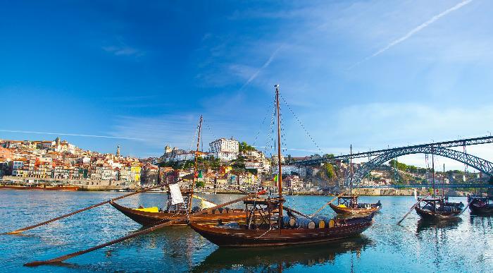 Ladjice na reki Douro plujejo ob jasnem sončnem vremenu. 