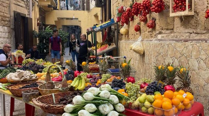 Pisana tržnica v italijanskem Bariju s sadjem zelenjavo in visečimi paradižniki ob ozki ulici starega mesta