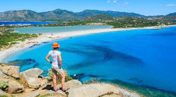 Popotnica občuduje turkizno morje in belo peščeno obalo z razgledne točke na Sardiniji