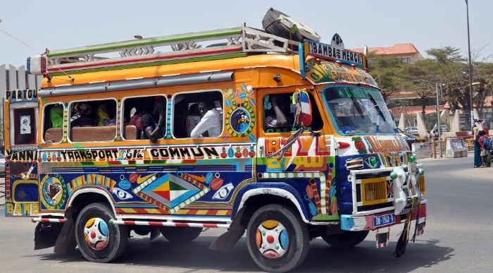 Do zadnjega mesta napolnjen pisani afriški avtobus s prtljago na strehi. 