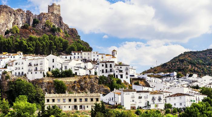 Španska bela vasica v Andaluziji obdana z zelenimi hribi in kronana z mogočno utrdbo na vrhu