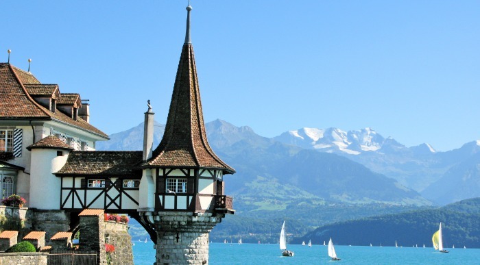 Grajski stolp nad jezerom polnem jadrnic s pogledom na gore. 