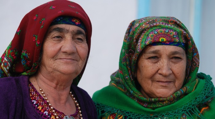 Nasmejani starejši gospe pokriti z pisanimi rutami zreta v daljavo. 